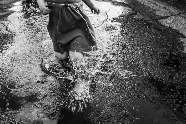 Toddler girl runs through puddle