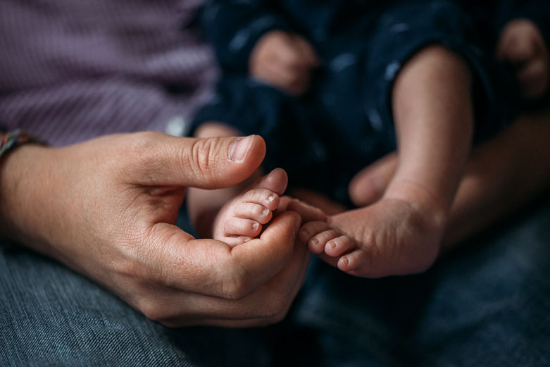 Father's hand touching baby's foot