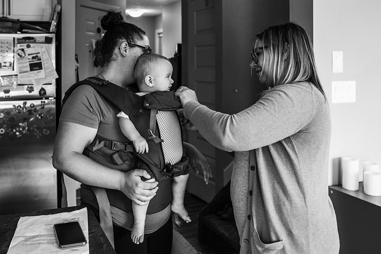 Edmonton postpartum doula adjusting baby carrier